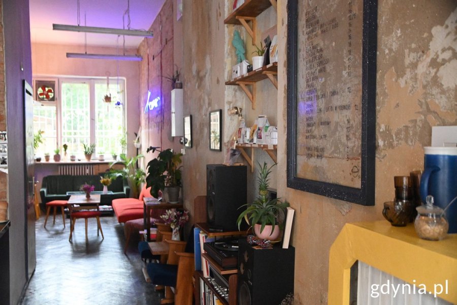 Wnętrze kawiarni „Kosmos” i meble: kanapy, stół oraz kwiaty