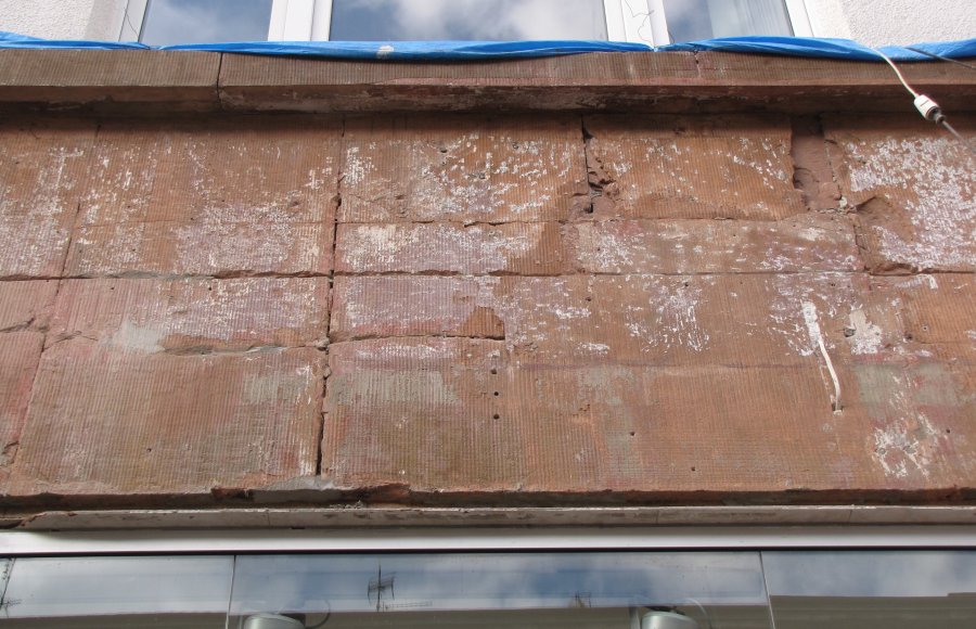 Okładzina z czerwonych płyt na parterze budynku PAGED w trakcie konserwacji – tj. po usunięciu warstwy styropianu a przed wypełnieniem szczelin. Widoczne pionowe dekoracyjne rowki na powierzchni płyt 