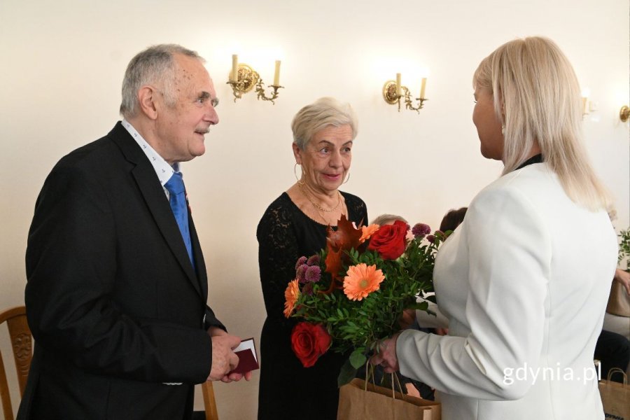 Agata Lipińska, zastępczyni kierownika USC wręcza seniorom kwiaty