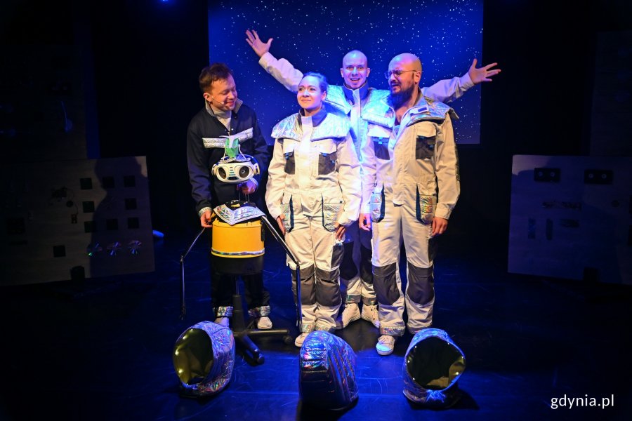Zdjęcie z próby spektaklu „Dlaczego nie lecimy do gwiazd?” w Teatrze Gdynia Główna. Na zdjęciu aktorzy wcielający się w astronautów i STASIU. W tle multimedia imitujące przestrzeń kosmiczną // fot. Magdalena Czernek