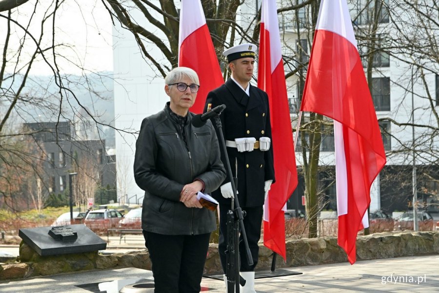 Joanna Zielińska, przewodnicząca Rady Miasta Gdyni, przemawiająca podczas obchodów 83. rocznicy zbrodni katyńskiej, które odbyły się na Cmentarzu Wojennym w  Redłowie. Za nią marynarz z posterunku honorowego stojący na tle biało-czerwonych flag // fot. Magdalena Czernek