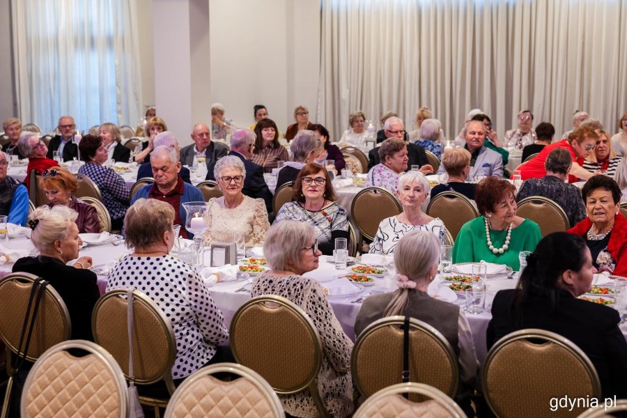 Grupa senior&oacute;w siedzi przy elegancko zastawionym stole
