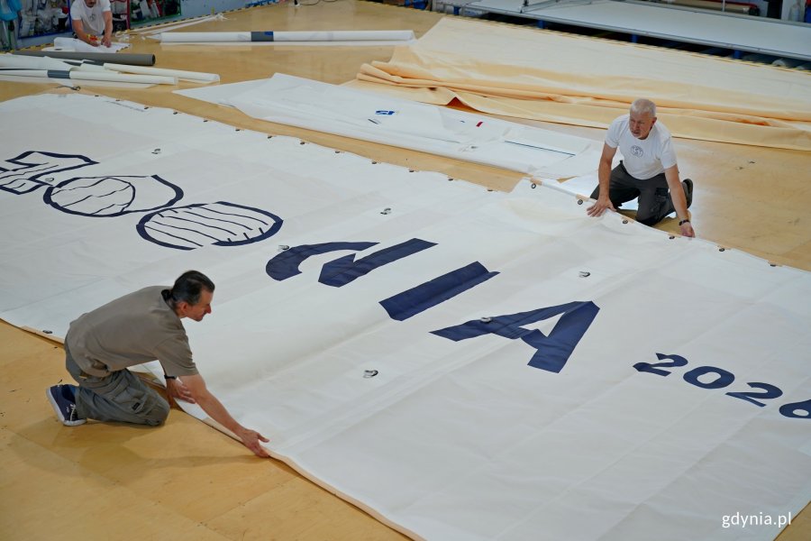 Pracownicy firmy Sail Service składający żagiel stulecia Gdyni 