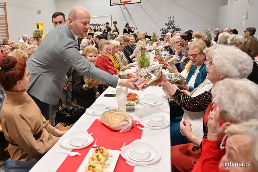 Wigilia dla seniorów w Przystani Chylońska 237, na zdjęciu wiceprezydent Bartoszewicz wręcza seniorom drobne upominki
