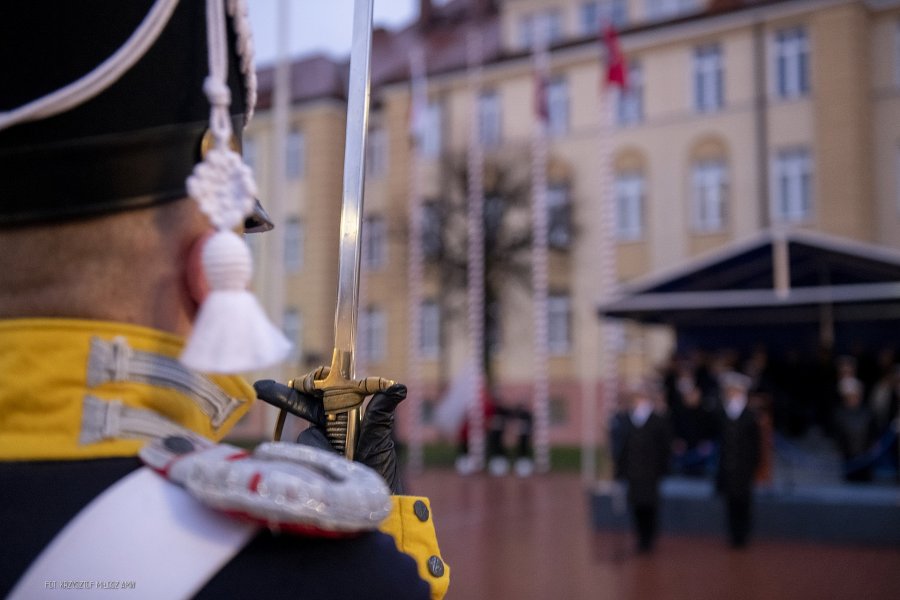 Podchorąży w historycznym mundurze prezentuje szablę.