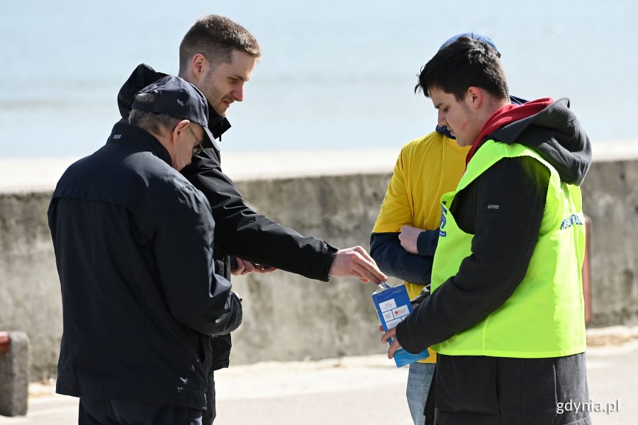 Dwaj mężczyźni w czarnych kurtkach wrzucają datki do puszki, którą trzymają wolontariusze kwestujący w ramach akcji „Pola Nadziei na Pomorzu” // fot. Michał Puszczewicz