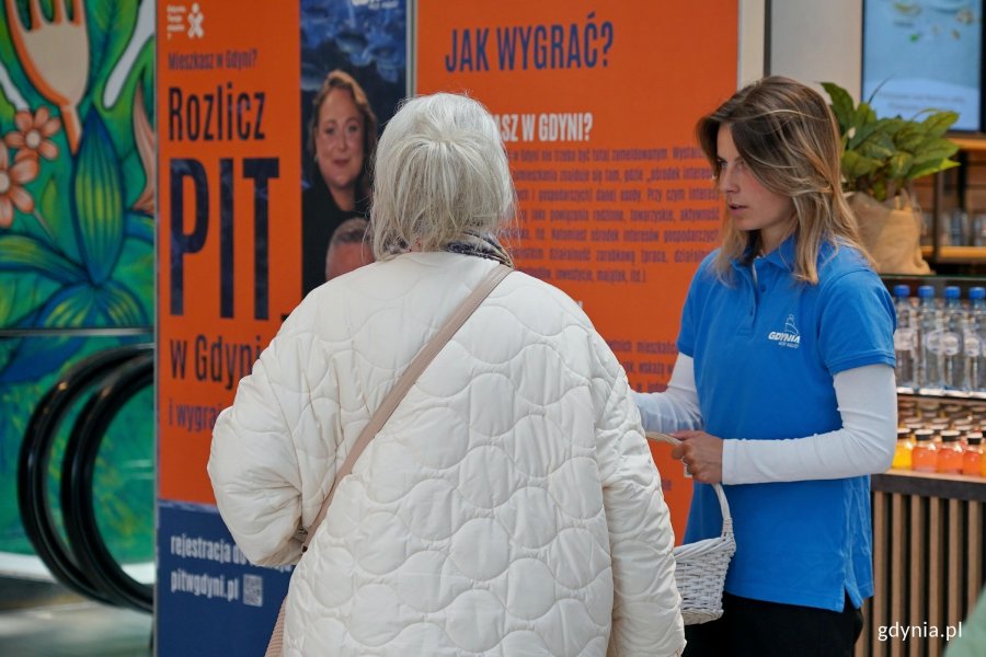 Konsultantka rozmawiająca z mieszkanką przy stoisku informacyjnym loterii &bdquo;Rozlicz PIT w Gdyni&rdquo; w Centrum Handlowym Batory 