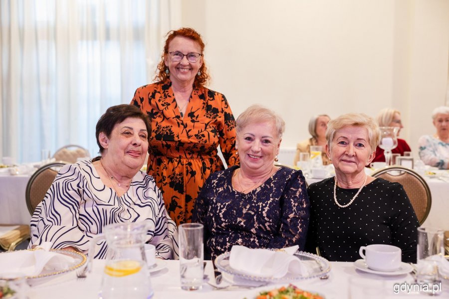 Cztery seniorki pozują do zdjęcia przy zastawionym świątecznie stole