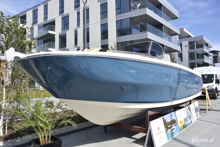 Kremowo-niebieski jacht stoi na nabrzeżu w Marinie Yacht Parku w Gdyni. W tle biało-szare budynki // fot. Magdalena Czernek