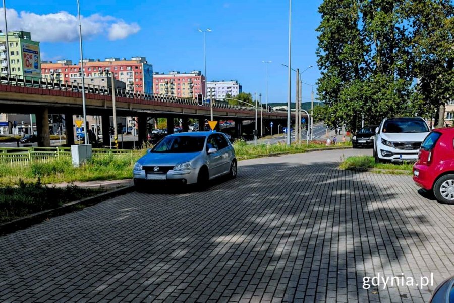 Samochody stojące na parkingu, w tle widoczna estakada