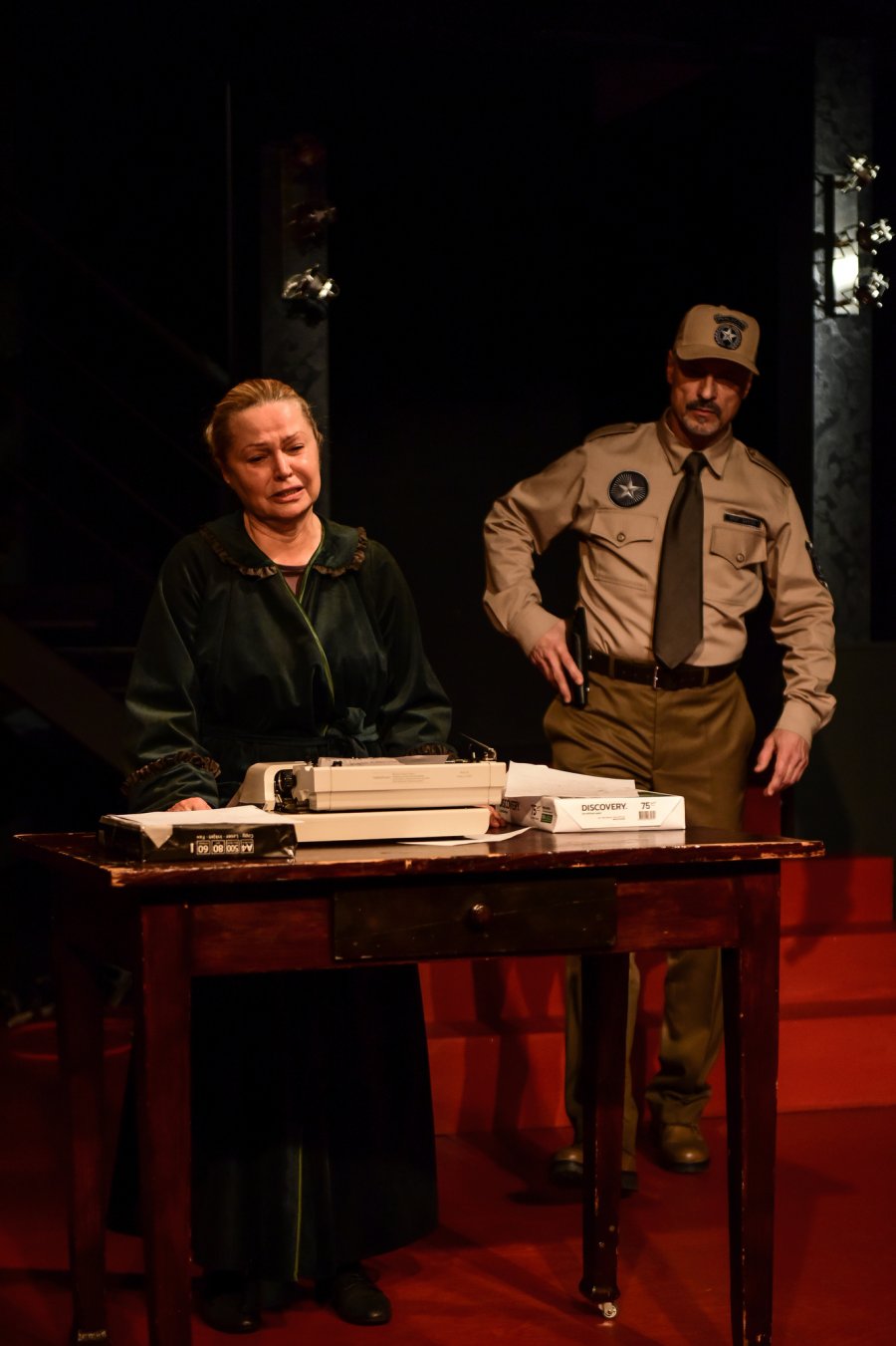 Zdjęcie z próby spektaklu „Misery” na podstawie powieści Stephena Kinga w reżyserii Krzysztofa Babickiego. Na fotografii: Dorota Lulka jako Annie Wilkes i Mariusz Żarnecki jako szeryf Buster. Annie stoi przy stole, na którym leży maszyna do pisania. W jej kierunku zmierza szeryf // fot. Roman Jocher
