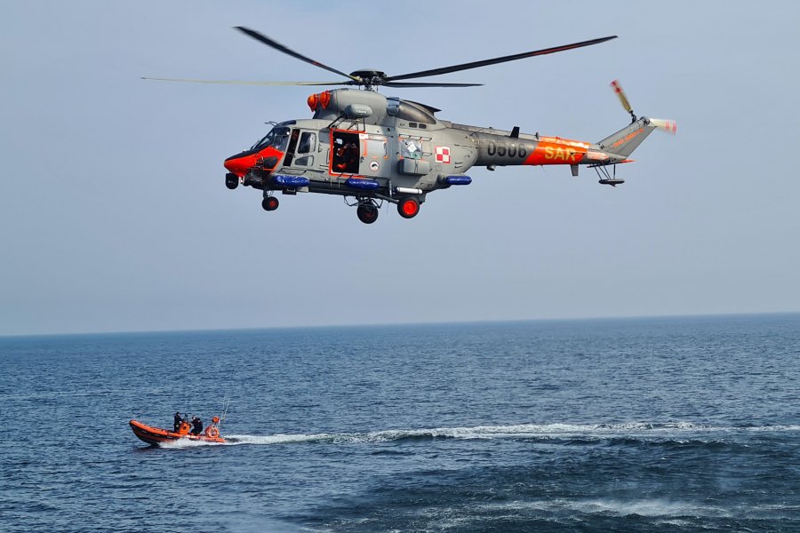 Śmigłowiec poszukiwawczo-ratowniczy "Anakonda" unosi się nad wodą podczas ćwiczeń taktycznych na Bałtyku. Pod nim, na wodzie płynie pomarańczowa łódź ratownicza // fot. archiwum dOW