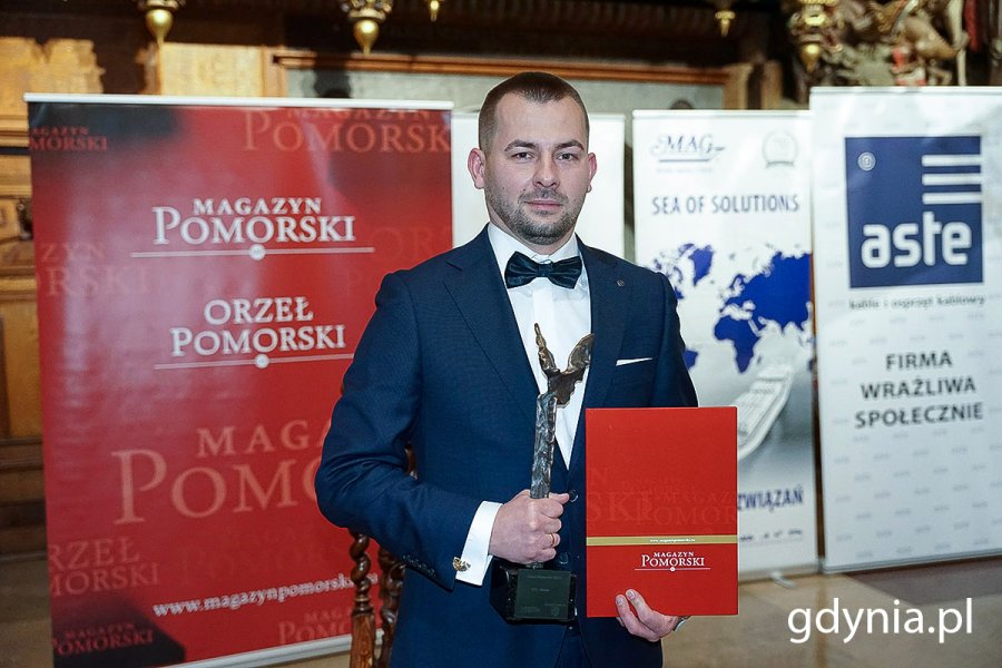 Na zdj. Robert Gulewicz, właściciel firmy GO-Estate ze statuetką „Orła Pomorskiego” stojący na te ścianki z napisem Magazyn Pomorski