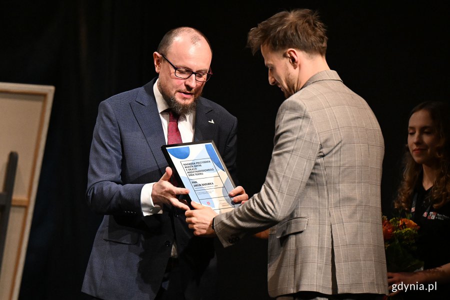 Mariusz Bzdęga - dyrektor zarządzający ds. kultury i aktywności mieszkańców wręcza Nagrodę Prezydent Miasta Gdyni z okazji Międzynarodowego Dnia Teatru aktorowi Jakubowi Badurce z Teatru Muzycznego w Gdyni