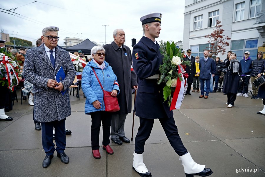 Andrzej Krajniak, Krzysztof Kozubowski i członkini stowarzyszenia Gdynian Wysiedlonych składający kwiaty podczas uroczystości upamiętniających 86. rocznicę pierwszych wysiedleń gdynian