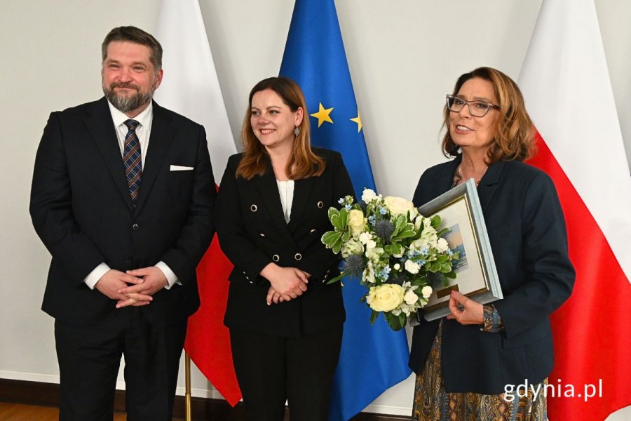 Przewodniczący Rady Miasta Gdyni Tadeusz Szemiot, prezydent Gdyni Aleksandra Kosiorek i marszałek Senatu Małgorzata Kidawa-Błońska stojący na tle flag Polski i Unii Europejskiej
