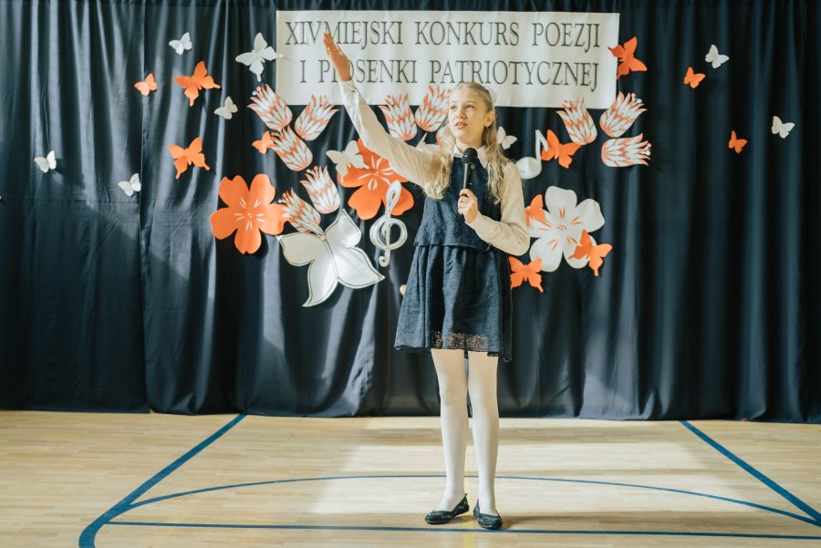 Dziewczynka na scenie podczas Miejskiego Konkursu Poezji i Piosenki Patriotycznej