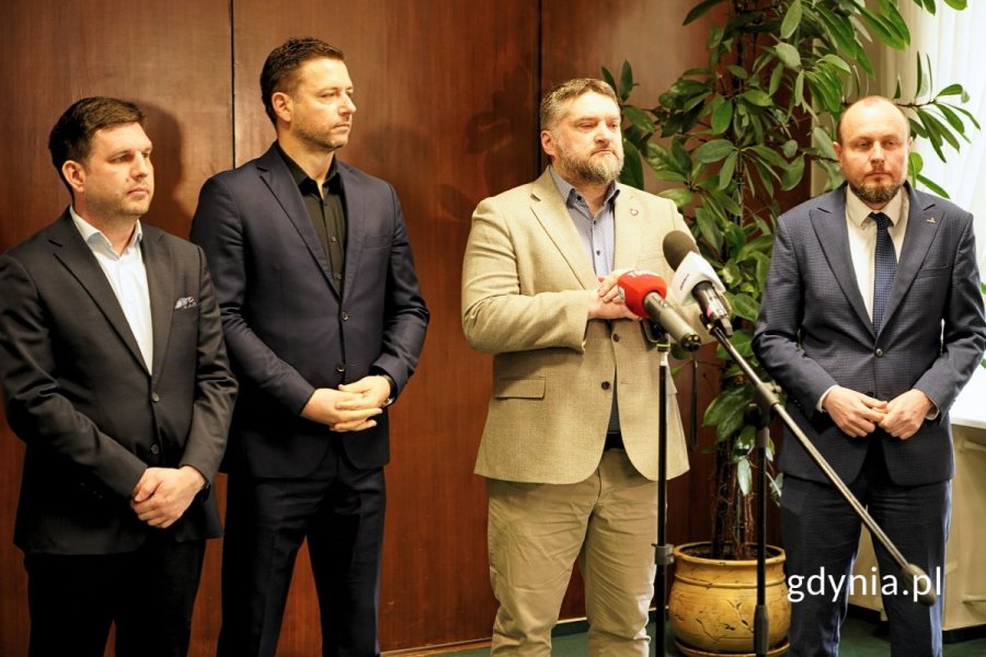 Stojący przed mikrofonami uczestnicy konferencji: Maciej Zielonka, wiceprezydent Gdyni; Wojciech Pertkiewicz, prezes zarządu Arki Gdynia; Tadeusz Szemiot, przewodniczący Rady Miasta Gdyni; Mariusz Bzdęga, dyrektor zarządzający ds. kultury i aktywności mieszkańców