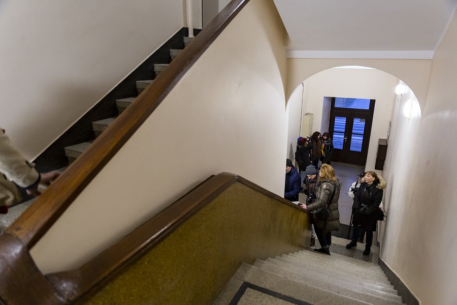 Grupa osób na klatce schodowej robi zdjęcia.