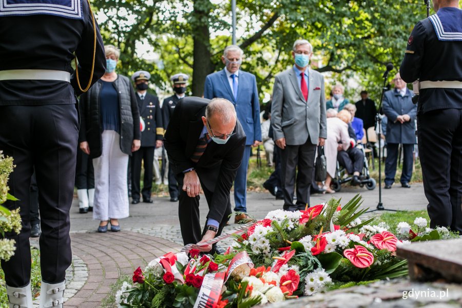 Wiceprezydent Gdyni Michał Guć składa kwiaty pod pomnikiem "W hołdzie zesłańcom Sybiru" podczas uroczystości z okazji Dnia Sybiraka. Pochyla się, żeby poprawić szarfę // fot. Karol Stańczak