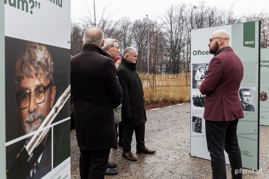 Bartosz Januszewski, kurator wystawy, opowiada o ekspozycji „Ryszard Kukliński” uczestnikom prezentacji, w tym prezydentowi Gdyni Wojciechowi Szczurkowi i radnemu Zenonowi Rodzie