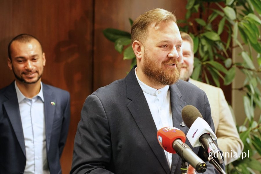 Łukasz Strzałkowski, radny Gdyni, stojący przy mikrofonach