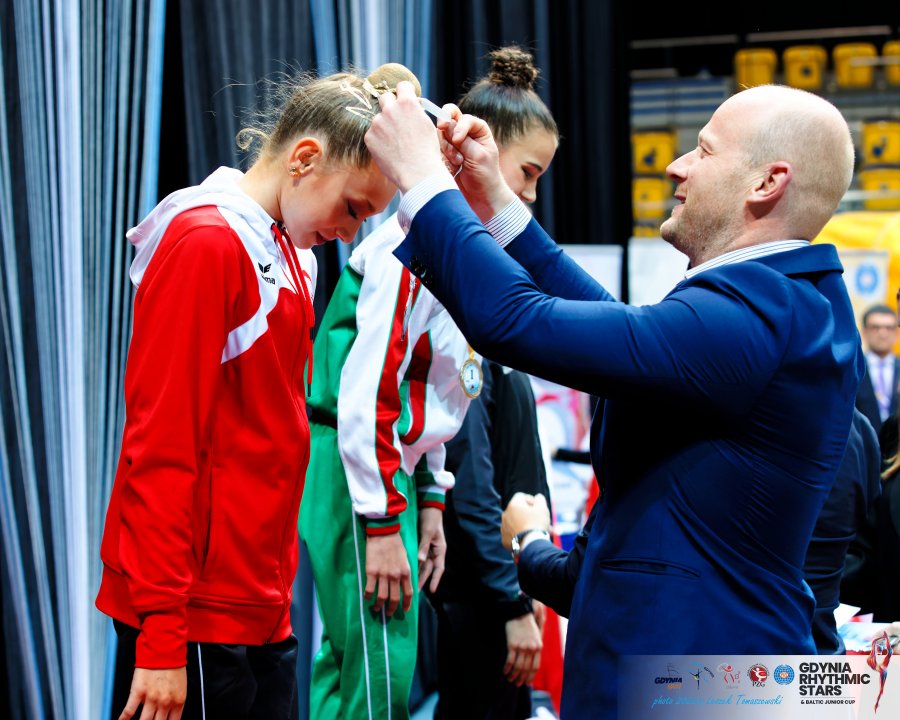 Wiceprezydent Bartoszewicz zakłada medal na szyję zwyciężczyni