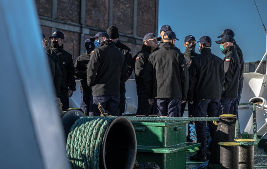 Podchorążowie Akademii Marynarki Wojennej w Gdyni na pokładzie statku "Horyzont II". Są ubrani w granatowe spodnie i czarne kurtki z przyszytymi do rękawów biało-czerwonymi flagami. Na głowach mają czapki z daszkiem, a na twarzach maseczki // fot. Piotr Lewandowski / Uniwersytet Morski w Gdyni