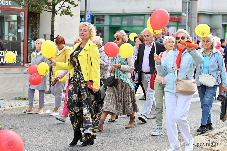 Uczestnicy przemarszu w ramach V Pomorskiego Dnia Seniora. W kolorowych strojach i z balonami w rękach.