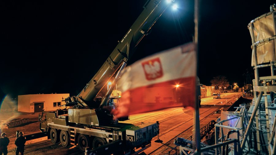 Biało-czerwona bandera na jednym z okrętów. Za nią widać nabrzeże i stojący na nim dźwig // fot. Michał Pietrzak / 3. Flotylla Okrętów