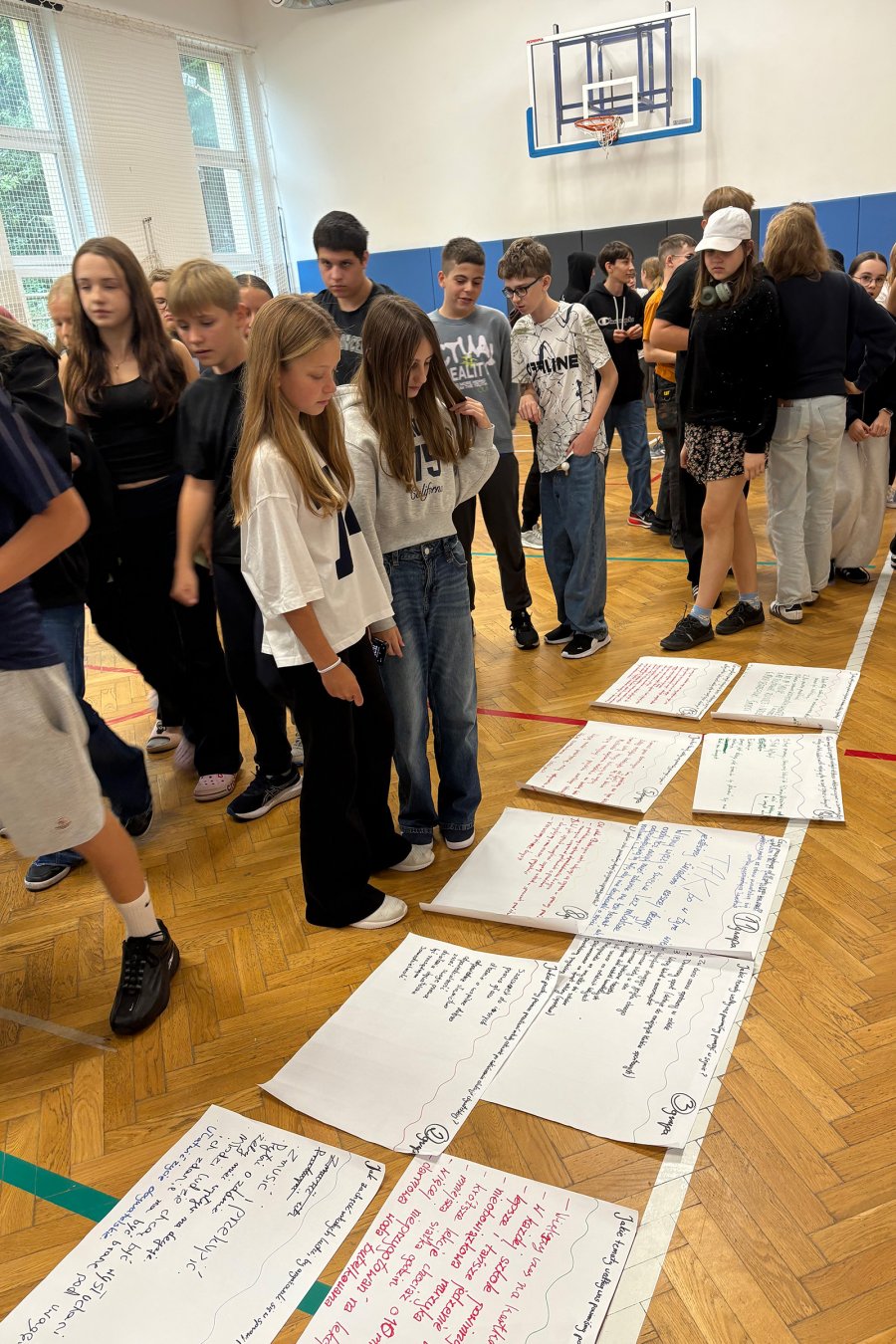 Młodzież stojąca nad pracami na podłodze w trakcie  debaty poświęconej edukacji obywatelskiej