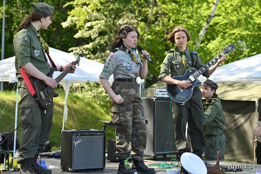 Występ harcerzy podczas festynu: wokalistka i dwóch harcerzy z gitarami