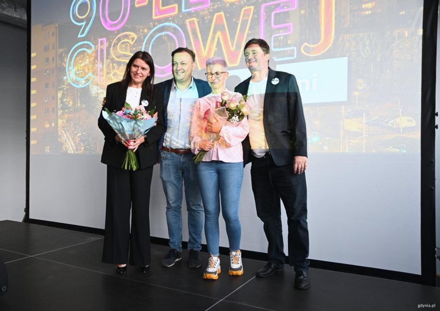 Dwóch mężczyzn i dwie kobiety z kwiatami na scenie