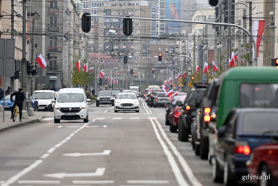Biało-czerwone flagi na masztach i słupach ozdobią ulicę 10 Lutego z okazji Święta Niepodległości. Na pierwszym planie ruch uliczny - samochody jadą po lewej i prawej stronie jezdni // fot. Michał Puszczewicz