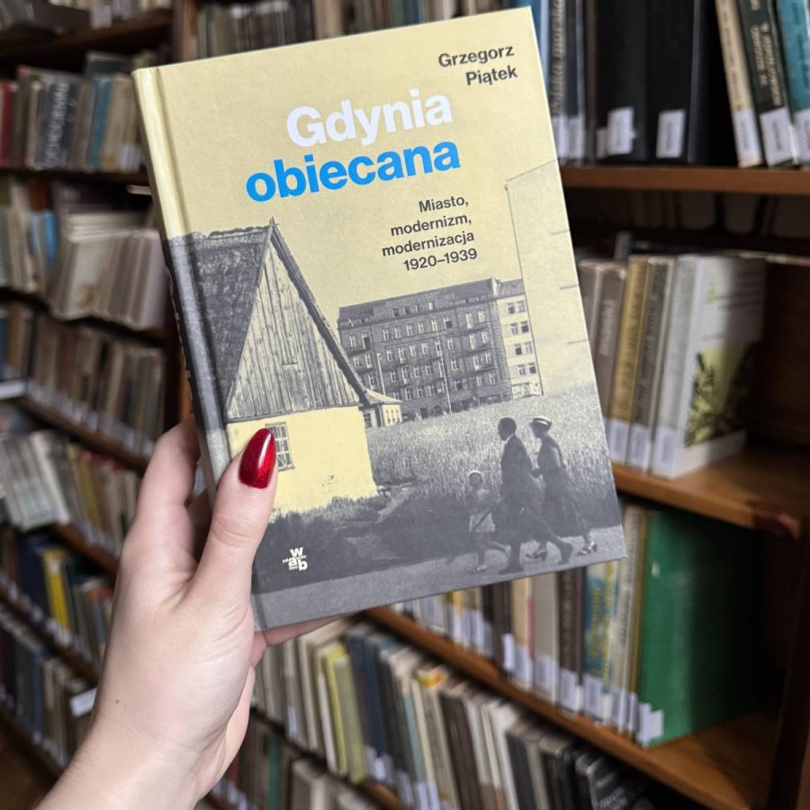 Kobieca dłoń trzymająca książkę „Gdynia obiecana. Miasto, modernizm, modernizacja 1920-1939”