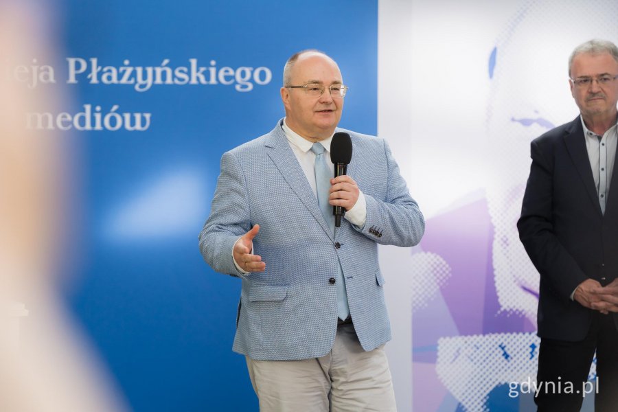 Mężczyzna w jasnej marynarce z mikrofonem