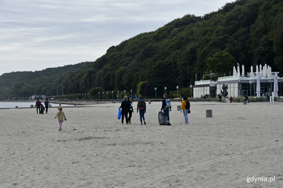 Grupa wolontariuszy na gdyńskiej plaży - biorą udział w akcji „Bałtycka Odyseja”. W rękach mają kolorowe worki i chwytaki // fot. Magdalena Czernek