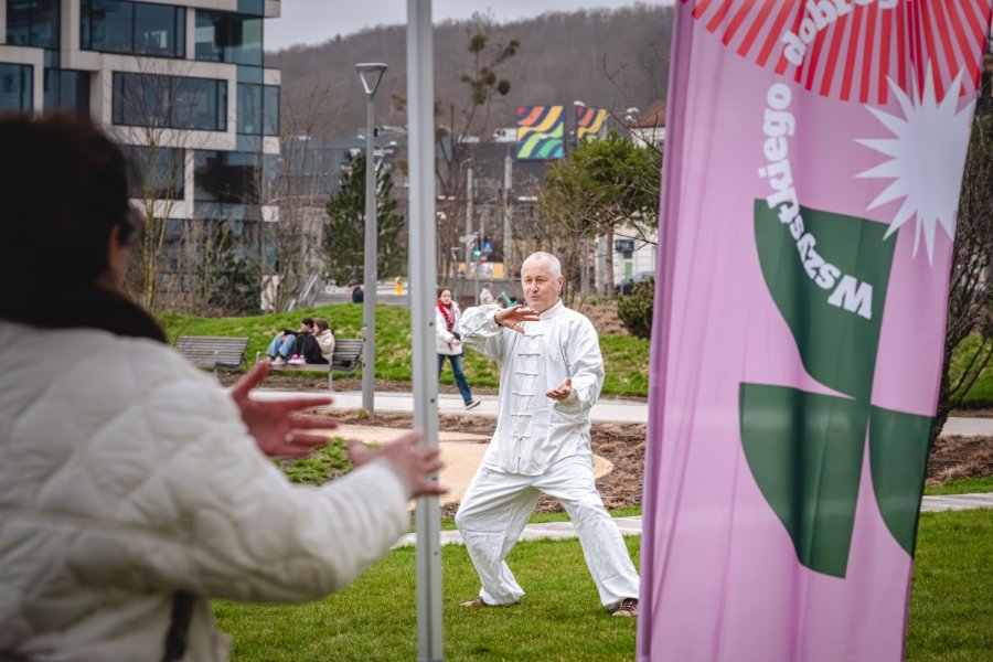  Tomasz Raganowicz prowadzący ćwiczenia tai chi w Parku Centralnym w ramach cyklu „Wszystkiego dobrego”. Po prawej: fragment flyera z napisem „Wszystkiego dobrego”