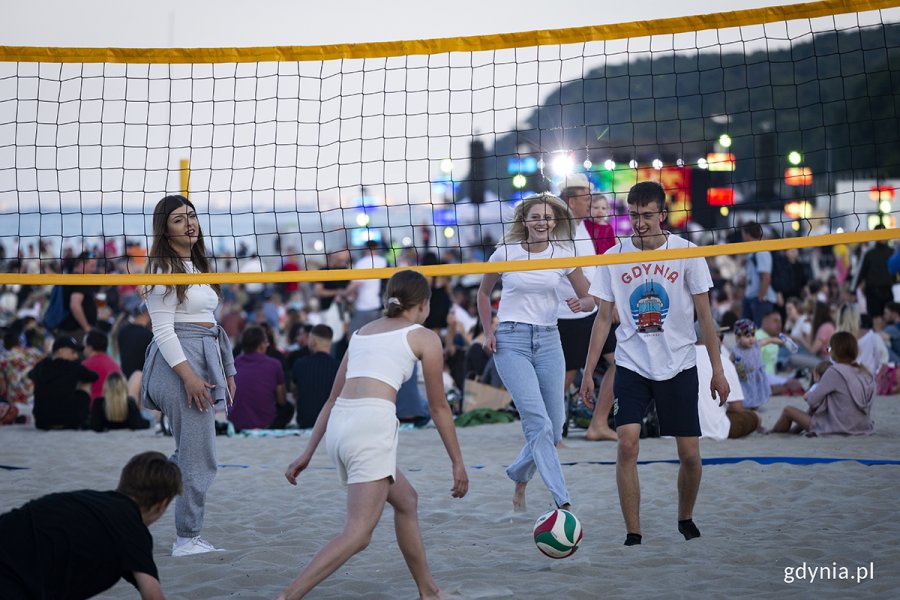 Młodzi ludzie grają w siatkówkę na plaży.