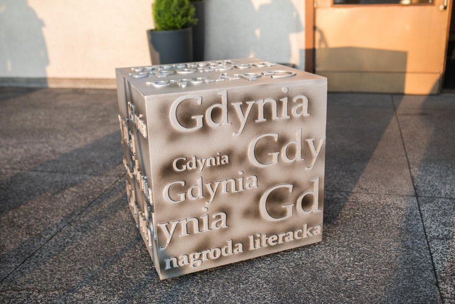 Statuetka Nagrody Literackiej Gdynia 2018: kostka z powtórzonymi napisami "Gdynia" oraz podpisem "Nagroda literacka". (fot. Karol Stańczak)