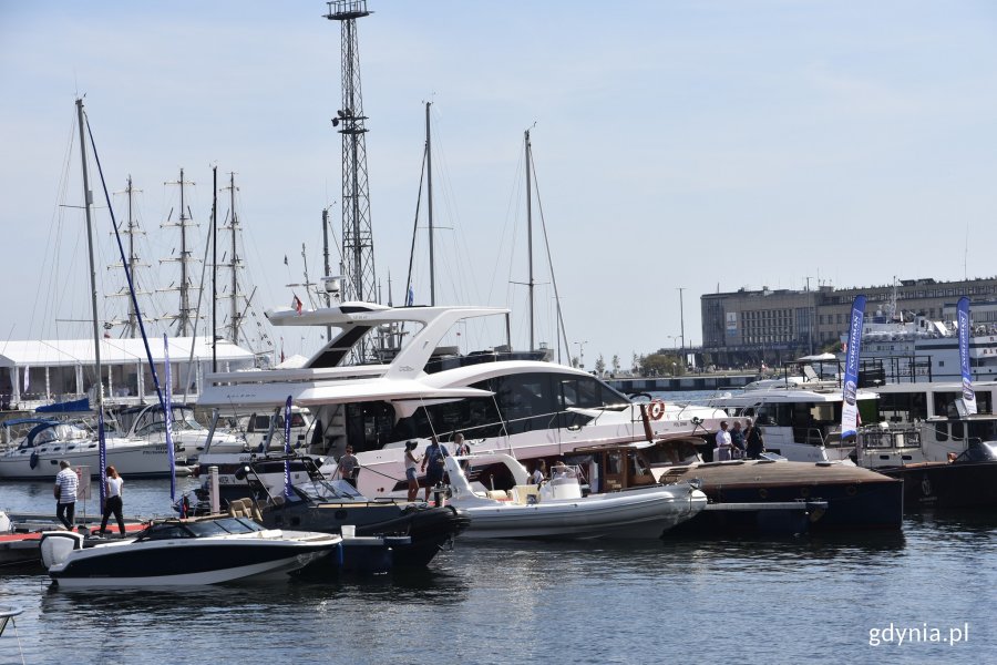 Różnego rodzaju jachty są zacumowane przy kei w Marina Yacht Parku w Gdyni. Na kei ludzie oglądający łodzie // fot. Magdalena Czernek