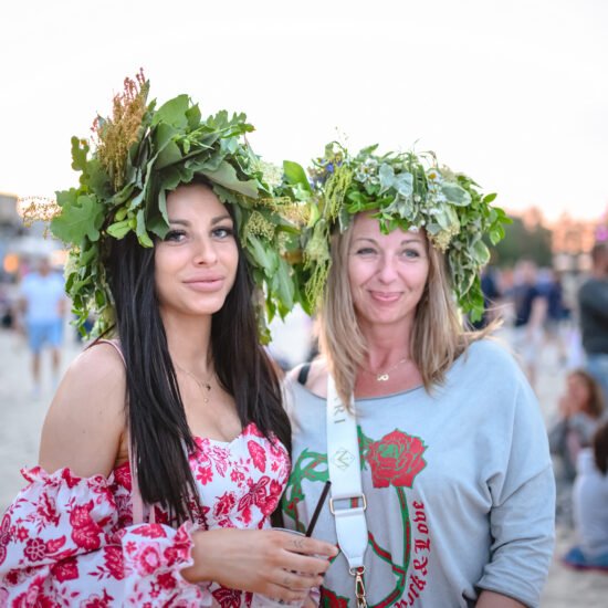 Festiwal Cudawianki. Dwie kobiety stojące na plaży w wiankach z kwiatów