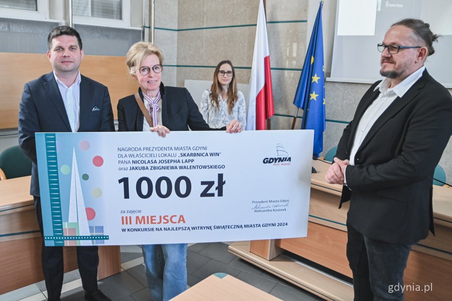 Wręczenie nagród w konkursie na najlepszą witrynę świąteczną w Gdyni - nagrodę odbiera przedstawicielka punktu Skarbnica Win (fot. Kamil Złoch)