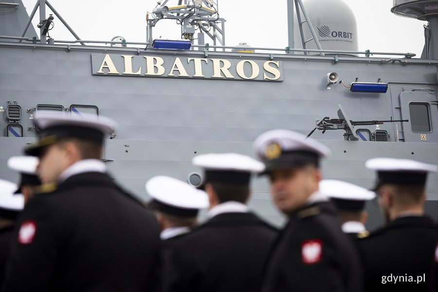 Burta okrętu z nazwą Albatros. Przed okrętem stoją marynarze.