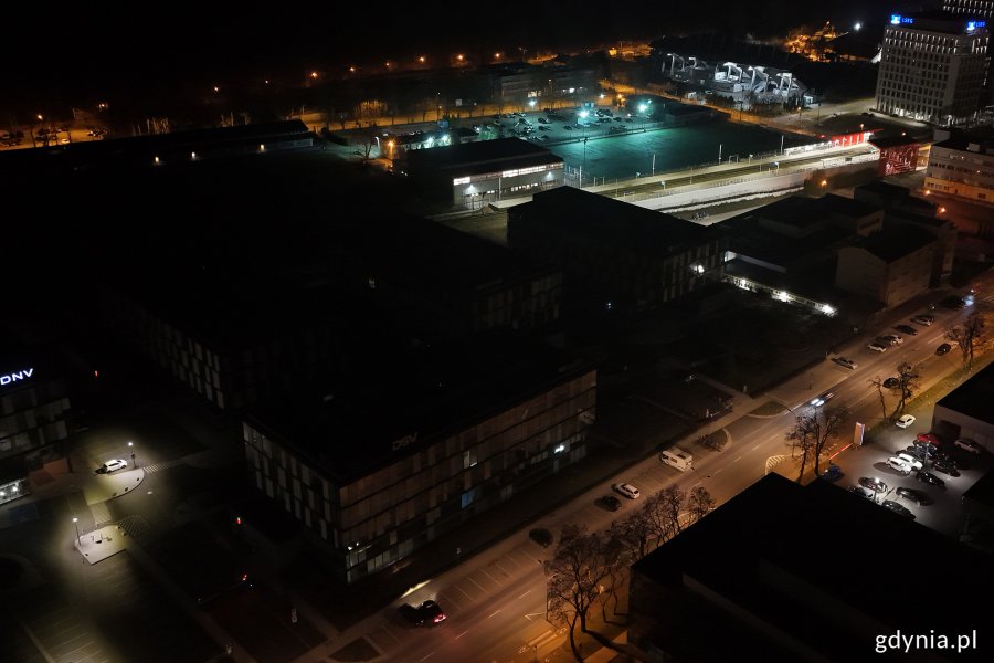 Nocne zdjęcie budynków, w których są zgaszone światła, stojących przy oświetlonych ulicach