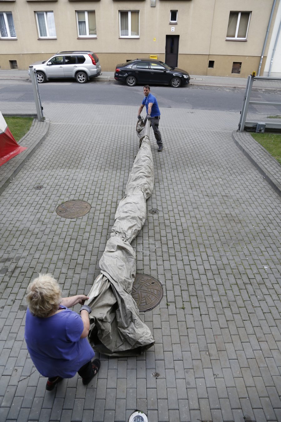 Specjaliści z Centrum Konserwacji Wraków Statków w Tczewie trzymają zwinięty żagiel z „Daru Pomorza” // fot. materiały prasowe Narodowego Muzeum Morskiego