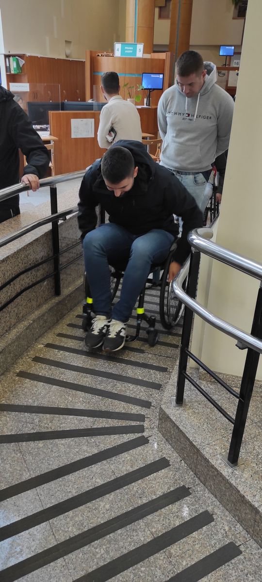 Policjant na wózku inwalidzkim próbuje poruszać się po budynku urzędu