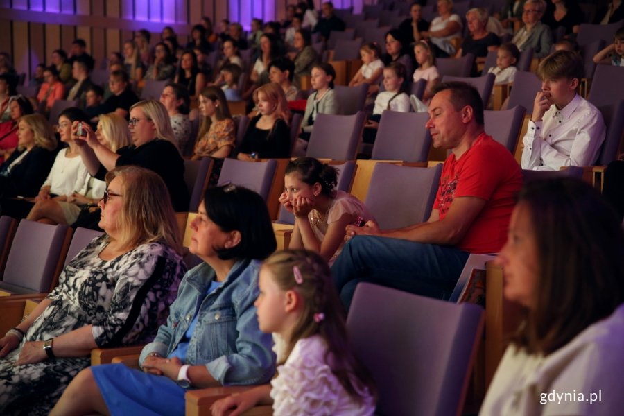 Widownia na sali konferencyjnej, na pierwszym planie dzieci.