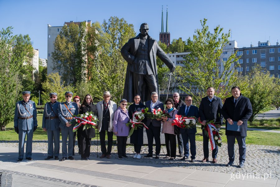 Ludzie z kwiatami po pomnikiem