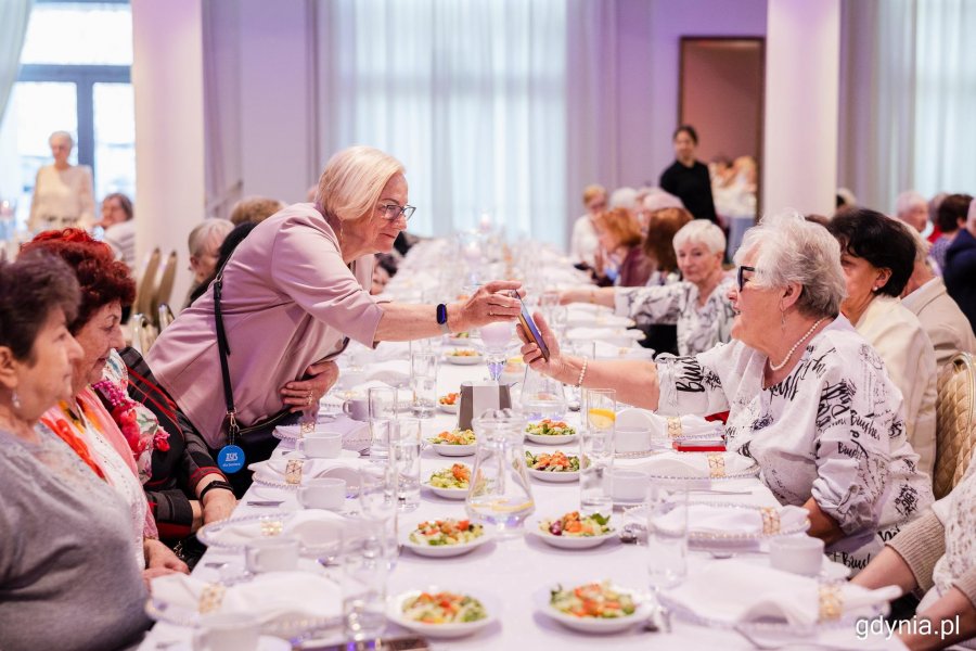 Grupa senior&oacute;w siedzi przy elegancko zastawionym stole